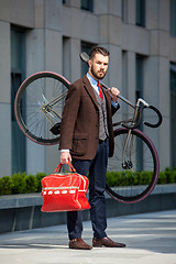 Image showing Handsome businessman carrying his bicycle 