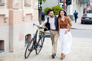 Image showing Young couple walking with bicycle and hugging