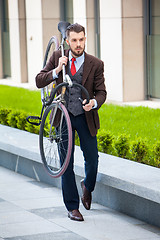 Image showing Handsome businessman carrying his bicycle