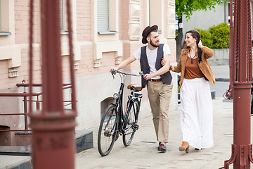 Image showing Young couple walking with bicycle and hugging