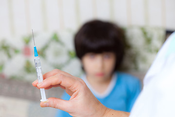 Image showing Doctor pediatrician with a syringe and a child in the background