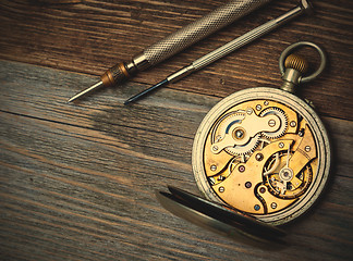 Image showing antique clock with an open mechanism and two screwdrivers