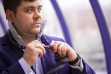 Image showing Serious businessman tying his tie