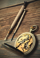 Image showing reverse side of the vintage pocket watch and a screwdriver