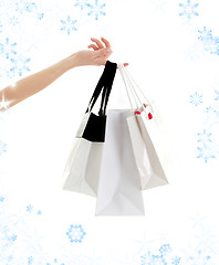 Image showing hand with shopping bags and snowflakes
