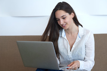 Image showing relaxed young woman at home working on laptop computer