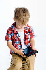 Image showing boy sitting on a pile of books with tablet computer