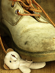 Image showing Teddy bear crushed by a heavy, old military boot.