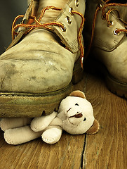 Image showing Teddy bear crushed by a heavy, old military boot.