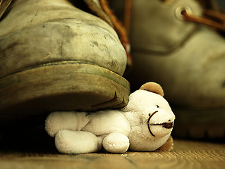 Image showing Teddy bear crushed by a heavy, old military boot.