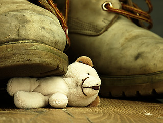 Image showing Teddy bear crushed by a heavy, old military boot.