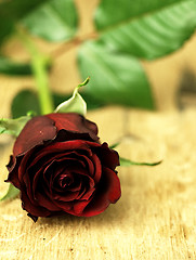 Image showing Red rose on a wooden table.