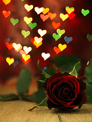 Image showing Red rose on a wooden table and hearts.