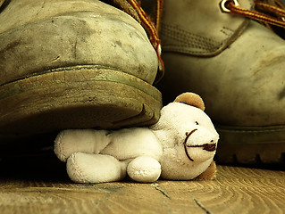 Image showing Teddy bear crushed by a heavy, old military boot.