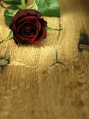 Image showing Red rose on a wooden table.