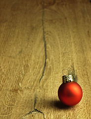 Image showing Red Christmas bauble on a wooden oak background.