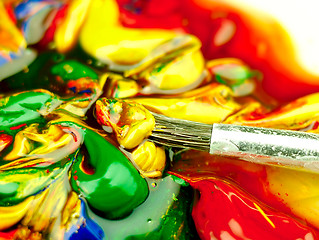 Image showing Colored paint mixed on palette. Dirty brush in the foreground.