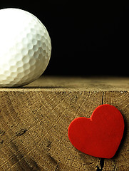 Image showing Golf ball and heart on the edge of table.