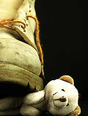 Image showing Teddy bear crushed by a heavy, old military boot.