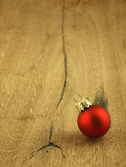 Image showing Red Christmas bauble on a wooden oak background.