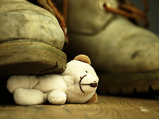 Image showing Teddy bear crushed by a heavy, old military boot.