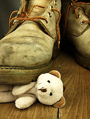 Image showing Teddy bear crushed by a heavy, old military boot.