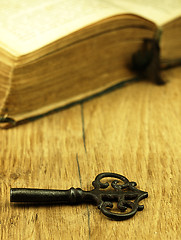 Image showing Key and old, open book with a damaged cover.