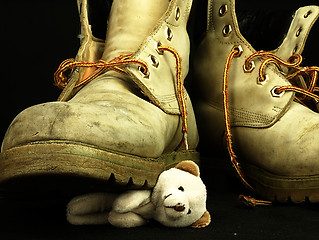 Image showing Teddy bear crushed by a heavy, old military boot.