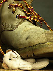 Image showing Teddy bear crushed by a heavy, old military boot.