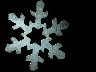 Image showing Huge white wooden snowflake and black background.
