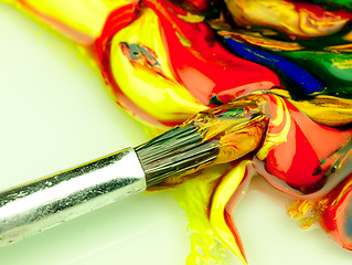 Image showing Colored paint mixed on palette. Dirty brush in the foreground.