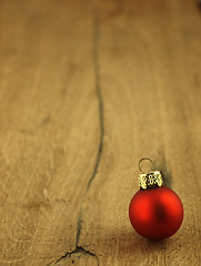 Image showing Red Christmas bauble on a wooden oak background.