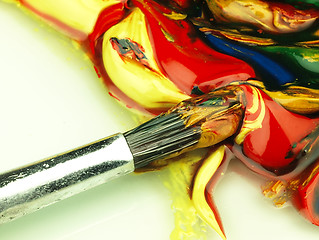 Image showing Colored paint mixed on palette. Dirty brush in the foreground.