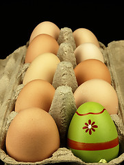 Image showing Colorful Easter egg in the company of ordinary eggs.