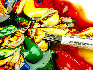 Image showing Colored paint mixed on palette. Dirty brush in the foreground.