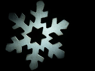 Image showing Huge white wooden snowflake and black background.