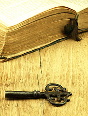 Image showing Key and old, open book with a damaged cover.