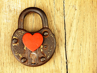 Image showing Rusty padlock and heart on a wooden background.