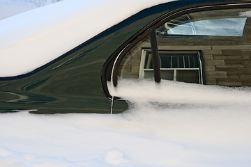 Image showing Car in the deep snow reflecting buildings around