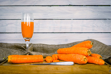 Image showing Carrot juice on a wooden board