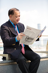 Image showing Senior businessman in suit reading newspaper