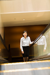 Image showing Young Asian female executive going up escalator