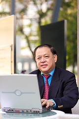 Image showing Senior Asian businessman in suit using laptop PC