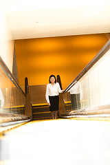 Image showing Young Asian female executive going up escalator