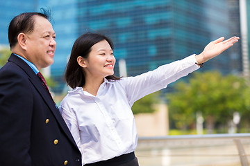 Image showing Senior businessman and young female executive pointing at a direction