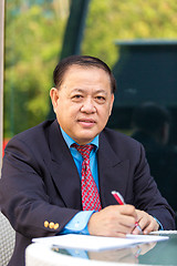 Image showing Senior Asian businessman in suit writing business proposal