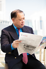 Image showing Senior businessman in suit reading newspaper