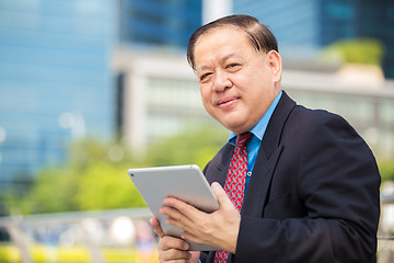 Image showing Senior Asian businessman in suit using tablet PC