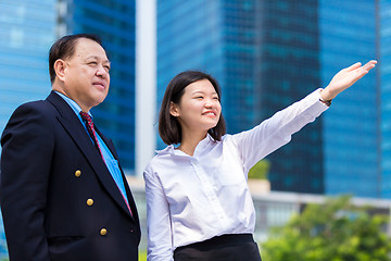 Image showing Senior businessman and young female executive pointing at a direction