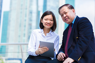 Image showing Senior businessman and young female executive using tablet PC